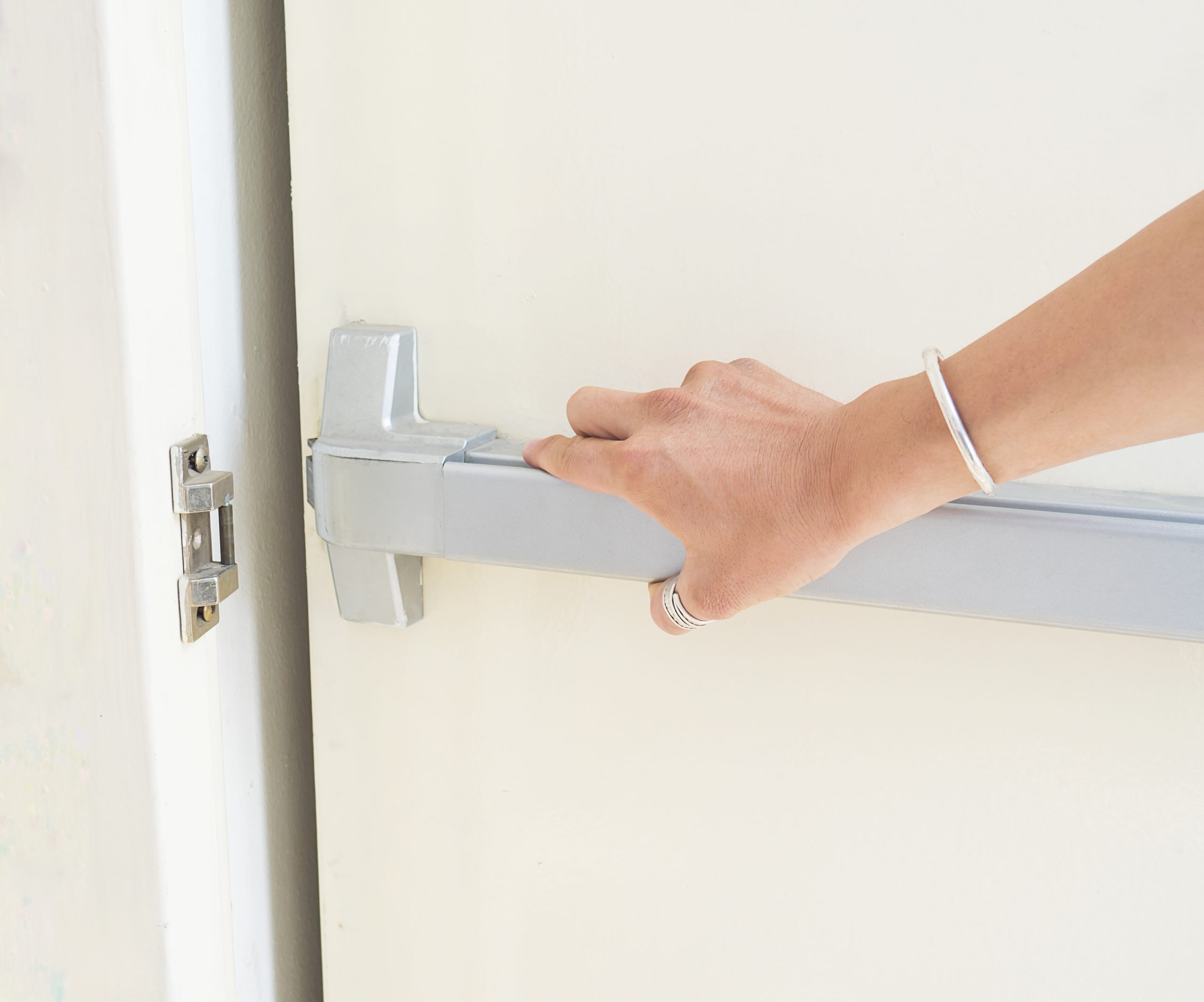 Hand is pushing/opening the emergency fire exit door